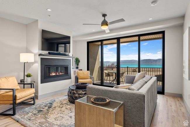 Living room with a glass covered fireplace, wood finished floors, ceiling fan, baseboards, and recessed lighting | Image 50