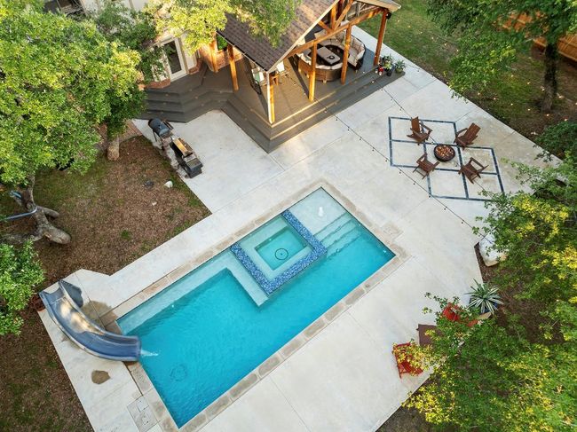 View of pool with a water slide, a pool with connected hot tub, and a patio area | Image 35