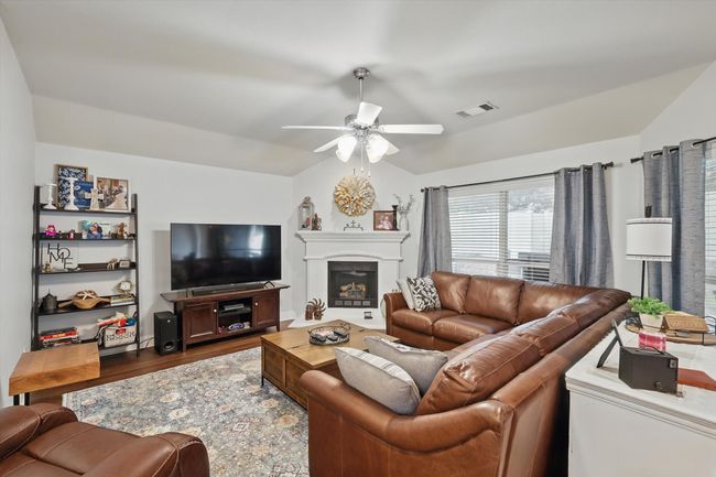 Living room featuring vaulted ceiling, a ceiling fan, wood finished floors, and a fireplace | Image 20