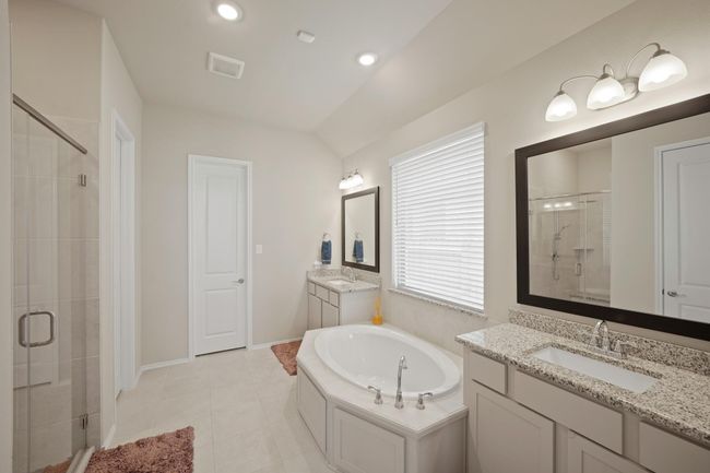 The primary bathroom features dual sinks, large window, tile floors, separate tub, and a walk-in shower with tile surround. | Image 21