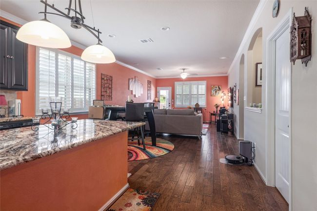 Kitchen with dark wood-type flooring, crown molding, arched walkways, light stone countertops, and ceiling fan | Image 6