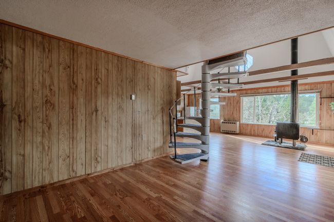 Unfurnished living room with a textured ceiling, light hardwood / wood-style floors, wooden walls, and heating unit | Image 18