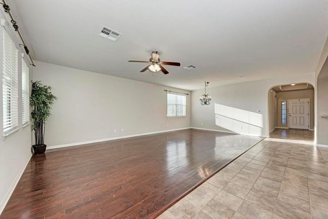 Unfurnished living room featuring ceiling fan, arched walkways, baseboards, and wood finished floors | Image 6