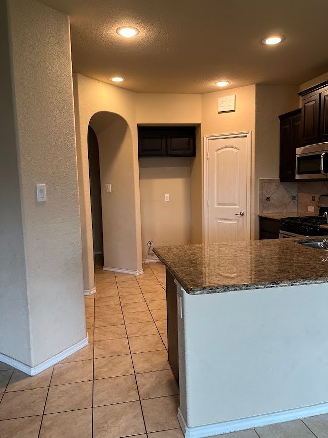Kitchen with gas range, stainless steel microwave, arched walkways, dark stone counters, and recessed lighting | Image 25