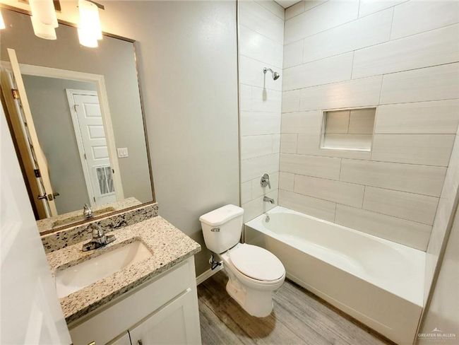 Bathroom with toilet, wood finished floors, vanity, baseboards, and bathing tub / shower combination | Image 14