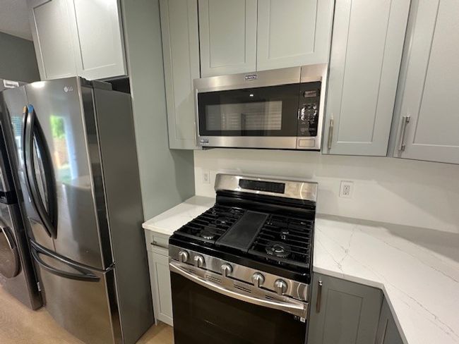 Kitchen featuring stainless steel appliances, gray cabinetry, and light stone counters | Image 11