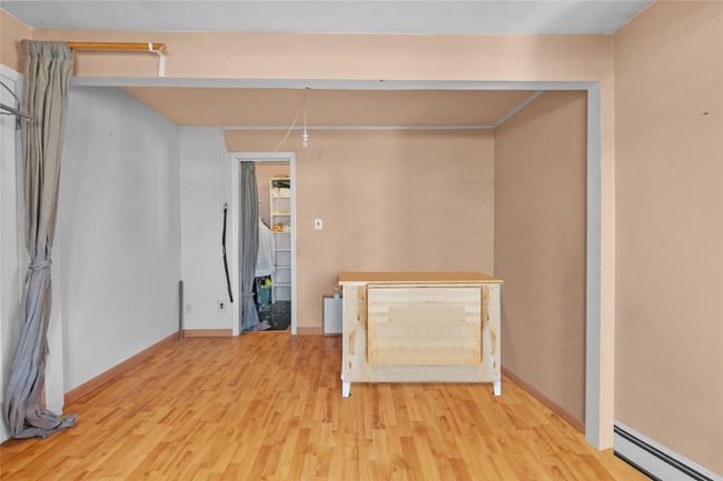 Unfurnished living room with baseboards, light wood finished floors, and baseboard heating | Image 13