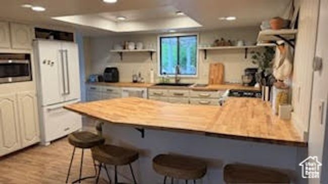 Kitchen with freestanding refrigerator, open shelves, a peninsula, a breakfast bar, and a tray ceiling | Image 8