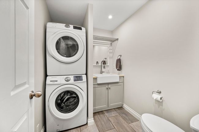 Clothes washing area with laundry area, a sink, wood tiled floor, baseboards, and stacked washer / drying machine | Image 18