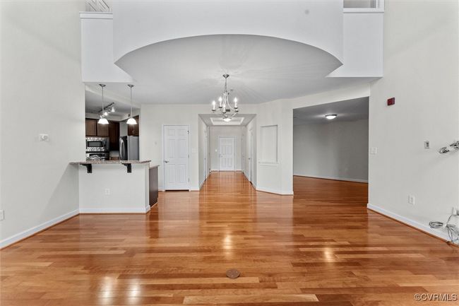 Unfurnished dining area with arched walkways, an inviting chandelier, light wood-style floors, and baseboards | Image 15