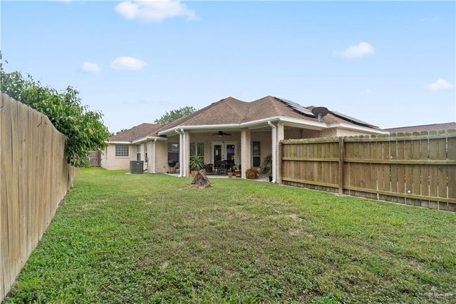 Rear view of property featuring ceiling fan, central AC unit, a patio, brick siding, and solar panels | Image 21