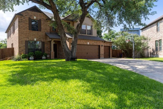 Traditional home featuring brick siding, concrete driveway, and an attached garage | Image 39