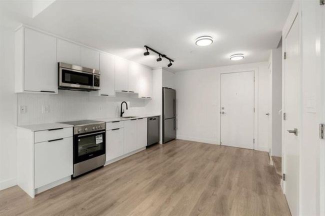 Kitchen featuring white cabinetry, appliances with stainless steel finishes, light wood-style flooring, and light countertops | Image 6