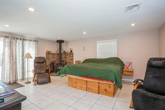 Bedroom featuring recessed lighting, a wood stove, and visible vents | Image 12