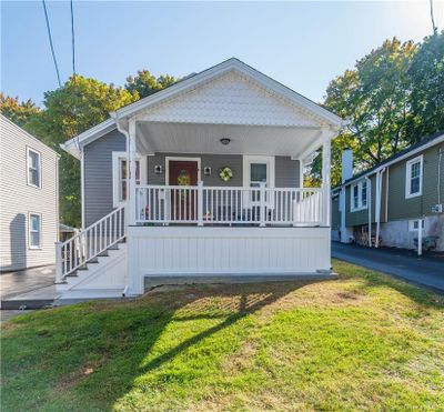 Bungalow-style house with covered porch and a front lawn | Image 1