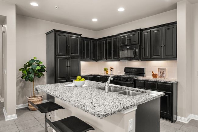 Kitchen with dark cabinetry, recessed lighting, black appliances, light tile patterned flooring, and light stone counters | Image 7