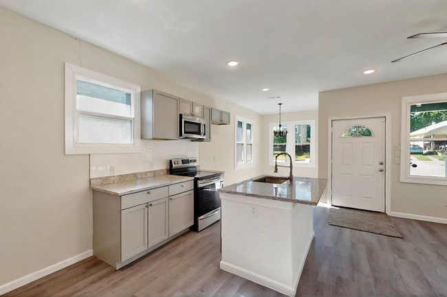 Kitchen with appliances with stainless steel finishes, a sink, light stone countertops, light wood-style floors, and recessed lighting | Image 5