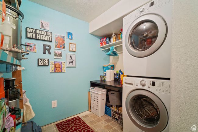 Washroom with a textured ceiling, stacked washer / drying machine, and laundry area | Image 26