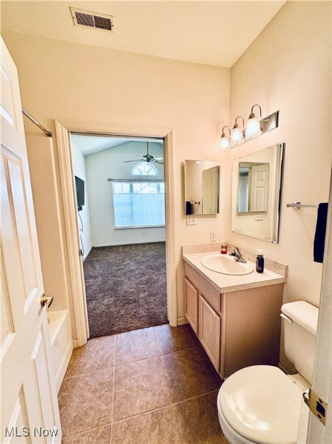 Bathroom with tile patterned floors, ceiling fan, toilet, vanity, and visible vents | Image 10
