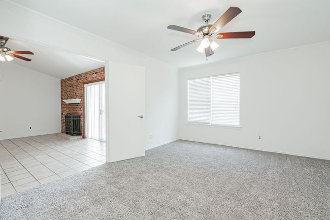 Unfurnished living room featuring carpet, a brick fireplace, crown molding, and ceiling fan | Image 18