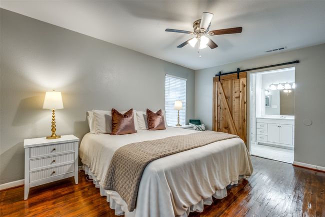 Bedroom with a barn door, hardwood / wood-style floors, ensuite bath, and a ceiling fan | Image 28