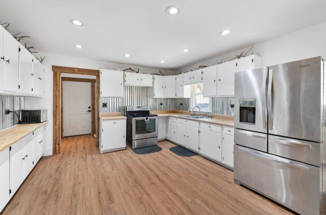 Kitchen featuring light countertops, white cabinetry, stainless steel appliances, and a sink | Image 7