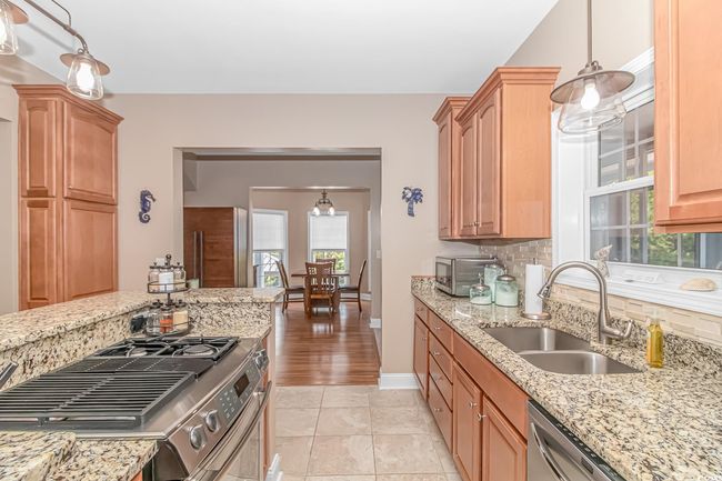 Kitchen featuring appliances with stainless steel finishes, decorative backsplash, light stone counters, and plenty of natural light | Image 9