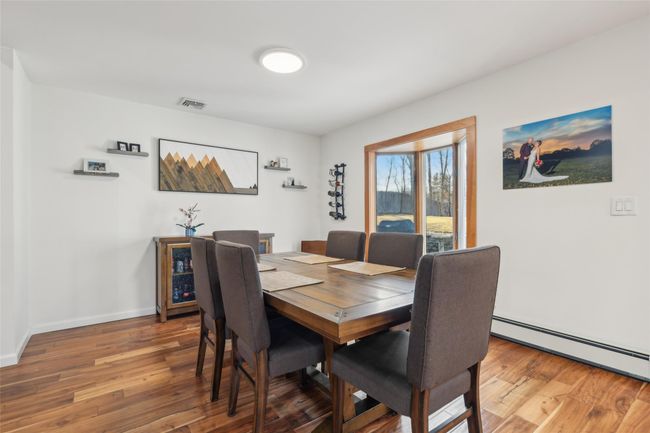 Dining room with visible vents, baseboards, wood finished floors, and a baseboard heating unit | Image 12