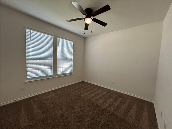 Unfurnished room featuring dark carpet, ceiling fan, and baseboards | Image 14
