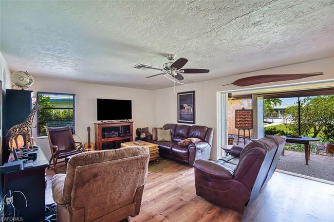 Living area featuring wood finished floors, a textured ceiling, and a ceiling fan | Image 11