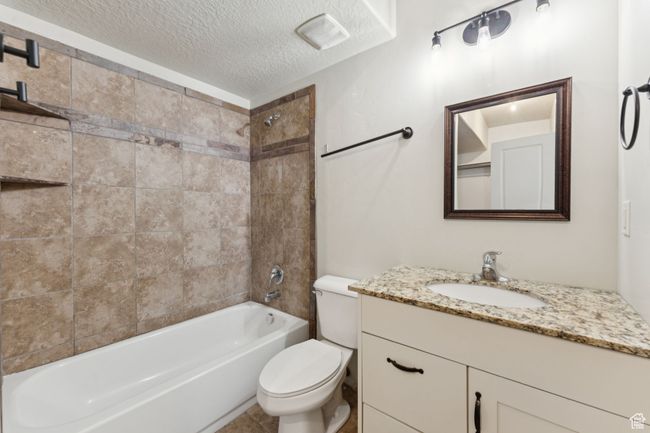 Bathroom featuring toilet, a textured ceiling, vanity, and bathtub / shower combination | Image 14