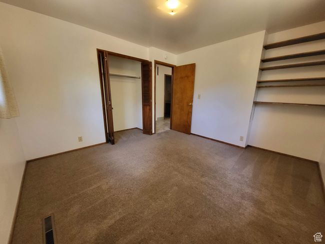 Unfurnished bedroom featuring dark colored carpet and a closet | Image 8