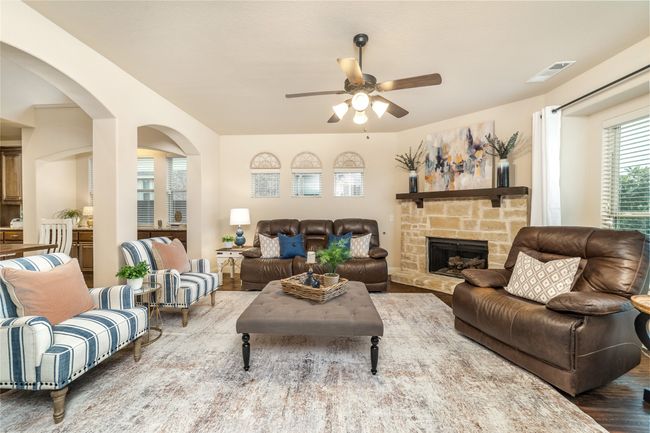 Living area with a ceiling fan, wood finished floors, a fireplace, and arched walkways | Image 13