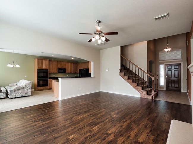 Unfurnished living room with stairs, light wood-type flooring, ceiling fan, baseboards, and a chandelier | Image 23