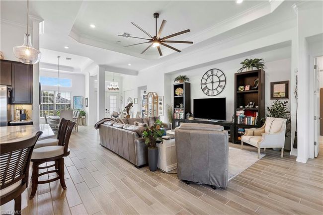 Living room with ceiling fan, crown molding, a raised ceiling, and wood tiled floor | Image 34