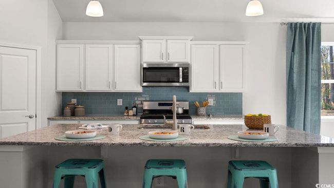 Kitchen with stainless steel appliances, backsplash, white cabinetry, and a breakfast bar | Image 7
