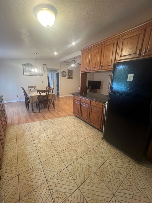 Kitchen with fridge, dark countertops, a textured ceiling, brown cabinetry, and built in desk | Image 12
