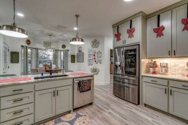 Kitchen featuring custom cabinetry, pendant lighting, sink, light hardwood / wood-style floors, and stainless steel appliances | Image 10