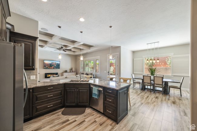 Kitchen with stainless steel appliances, dark brown cabinets, a ceiling fan, a sink, and light wood-type flooring | Image 12
