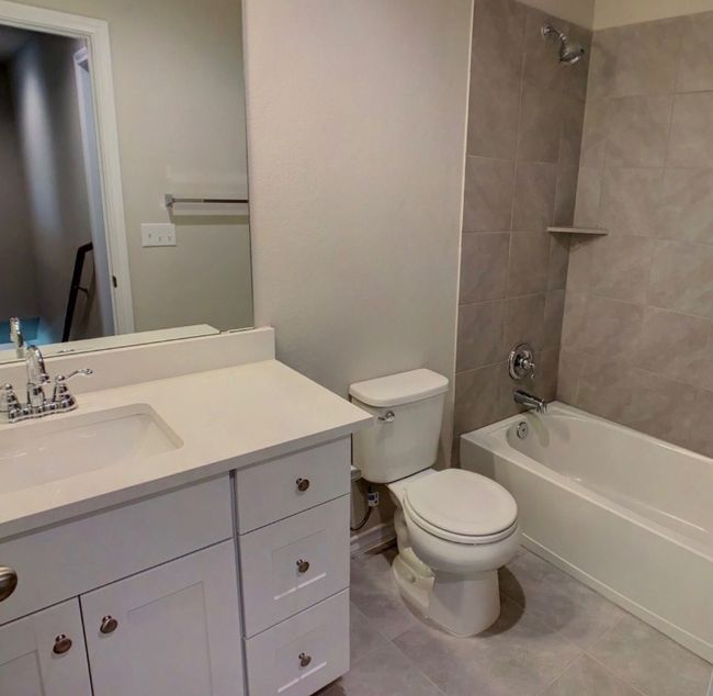 Bathroom with shower / bathing tub combination, tile patterned floors, toilet, and vanity | Image 17
