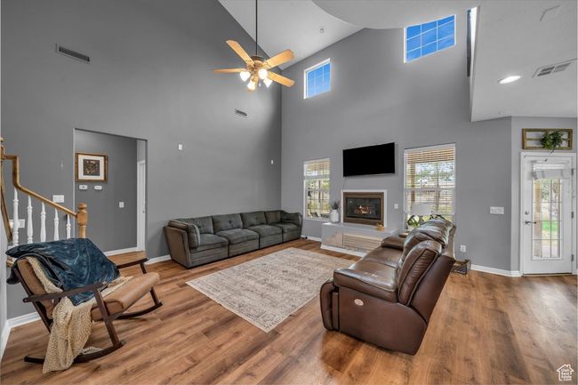 Living room featuring wood finished floors, a ceiling fan, visible vents, and a high ceiling | Image 14