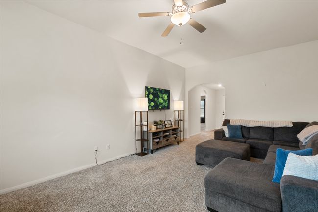 Carpeted living area with arched walkways, ceiling fan, and baseboards | Image 8