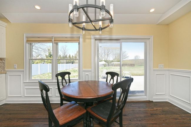 Dining space featuring a decorative wall, dark wood-style flooring, a wainscoted wall, and a chandelier | Image 19