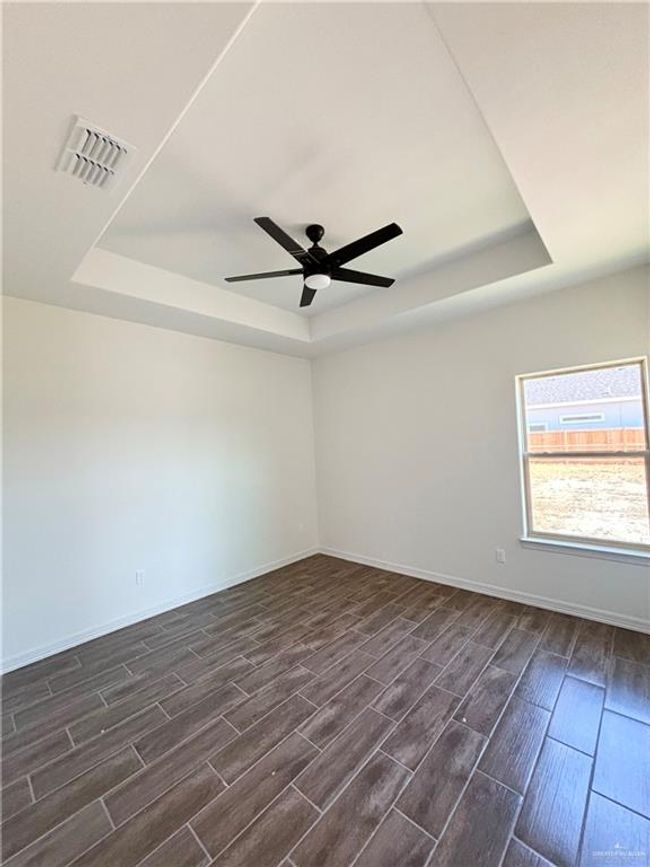 Empty room with wood finish floors, a tray ceiling, and visible vents | Image 10