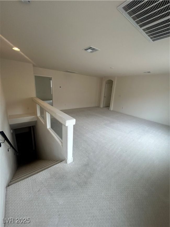 Unfurnished living room featuring carpet flooring, arched walkways, and stairs | Image 11