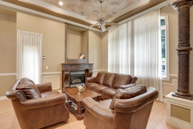 Living room with crown molding, a tray ceiling, a glass covered fireplace, light wood-type flooring, and a ceiling fan | Image 8