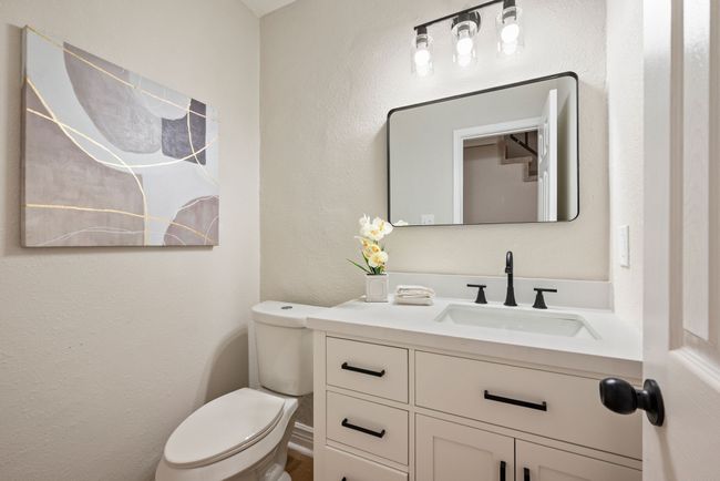 Powder bathroom has been nicely updated with modern lighting, a framed mirror, and a sleek vanity with black hardware. | Image 20