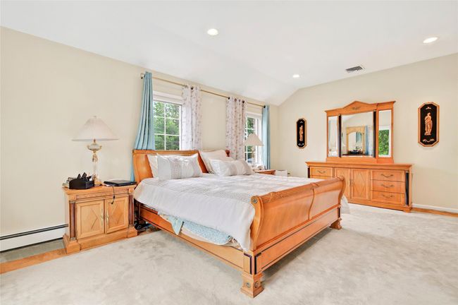 Bedroom featuring vaulted ceiling, light carpet, recessed lighting, and a baseboard heating unit | Image 28
