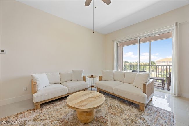 Living room with light tile patterned floors, ceiling fan, lofted ceiling, and baseboards | Image 22