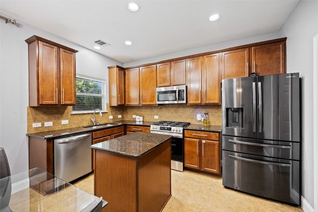 Kitchen featuring stainless steel appliances, dark stone counters, tasteful backsplash, recessed lighting, and a kitchen island | Image 9